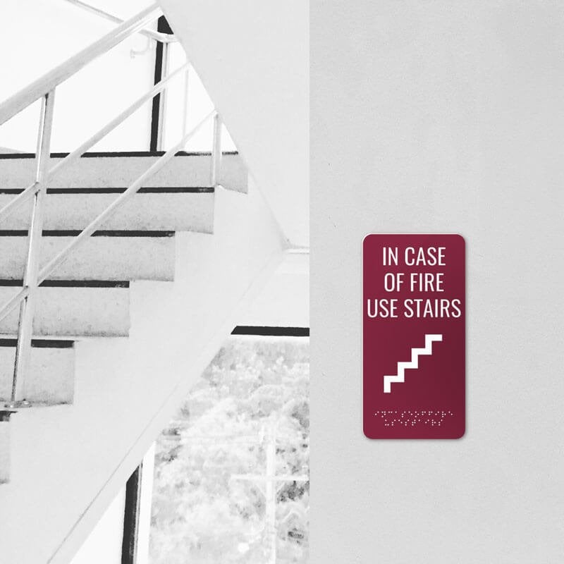 Vertical ADA sign for a fire exit by stairs