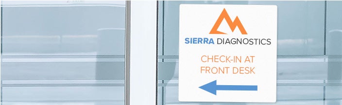 White plastic sign with colored text saying SIERRA DIAGNOSTICS CHECK IN AT FRONT DESK with a company logo and an arrow