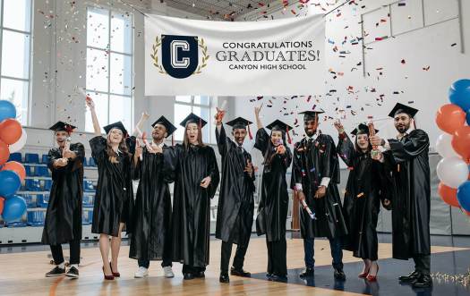 Students celebrating their graduation under a Graduation Banner