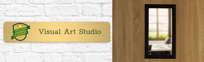 Full-color brass sign posted beside a classroom door that says Visual Art Studio with a black and green logo to the left