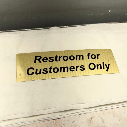 An Oxidized Custom Engraved Brass Plate Saying Restroom for Customers Only 