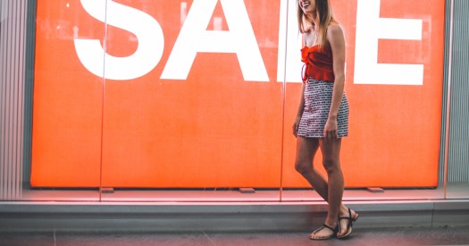 Woman Standing in Front of an Orange SALE Sign